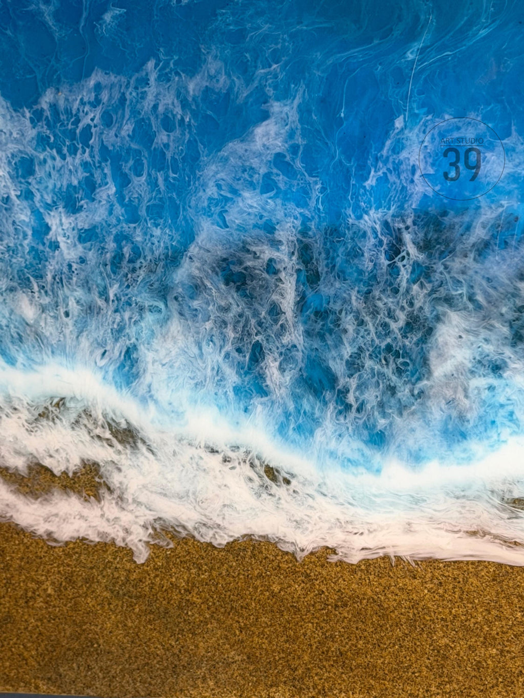 Abstract artwork depicting a beach scene with a blue ocean and foamy white waves crashing onto a golden sand shore. The number "39" is visible in the upper right corner.