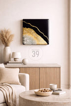 Square black and gold abstract art piece with a gold vein design. The artwork is mounted on a white wall above a wooden cabinet. The text "ART STUDIO 39" is in a circle below the artwork.