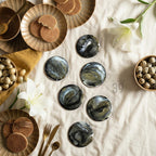 Six round coasters with a black, white, and gold abstract design are arranged on a white surface. The coasters are surrounded by plates of cookies, bowls of eggs, and gold utensils. The image also includes the text "ART STUDIO 39".