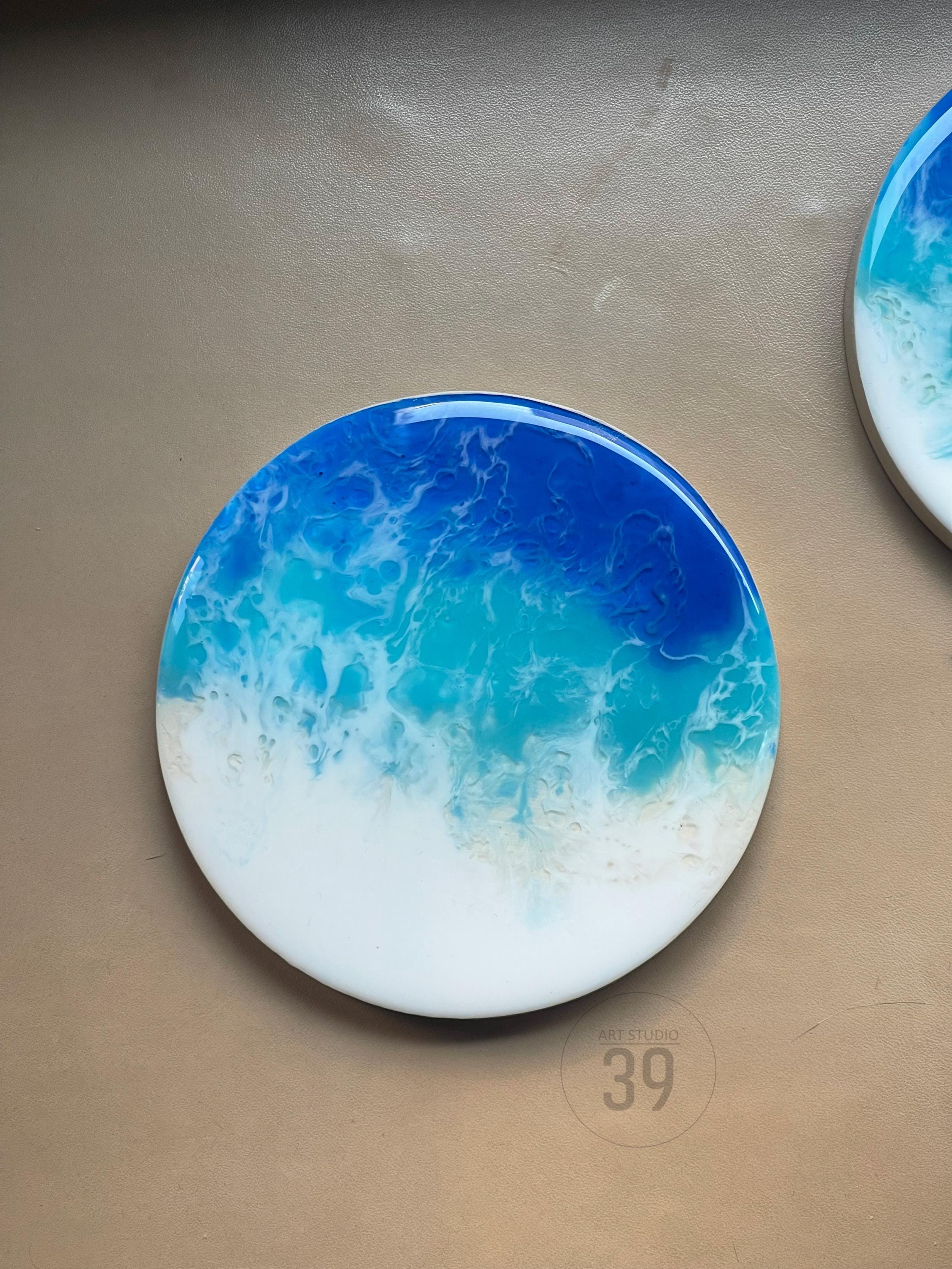 Round coaster with an ocean wave design. The coaster features shades of blue, turquoise, and white, resembling a seascape. The coaster is a decorative item with a glossy finish. The text "ART STUDIO 39" is printed on the coaster.