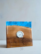 A wooden desk clock with a blue resin top. The clock face is white with black Roman numerals and hands. The base is engraved with "Merry Christmas from Tom". The clock is approximately 4 inches tall.