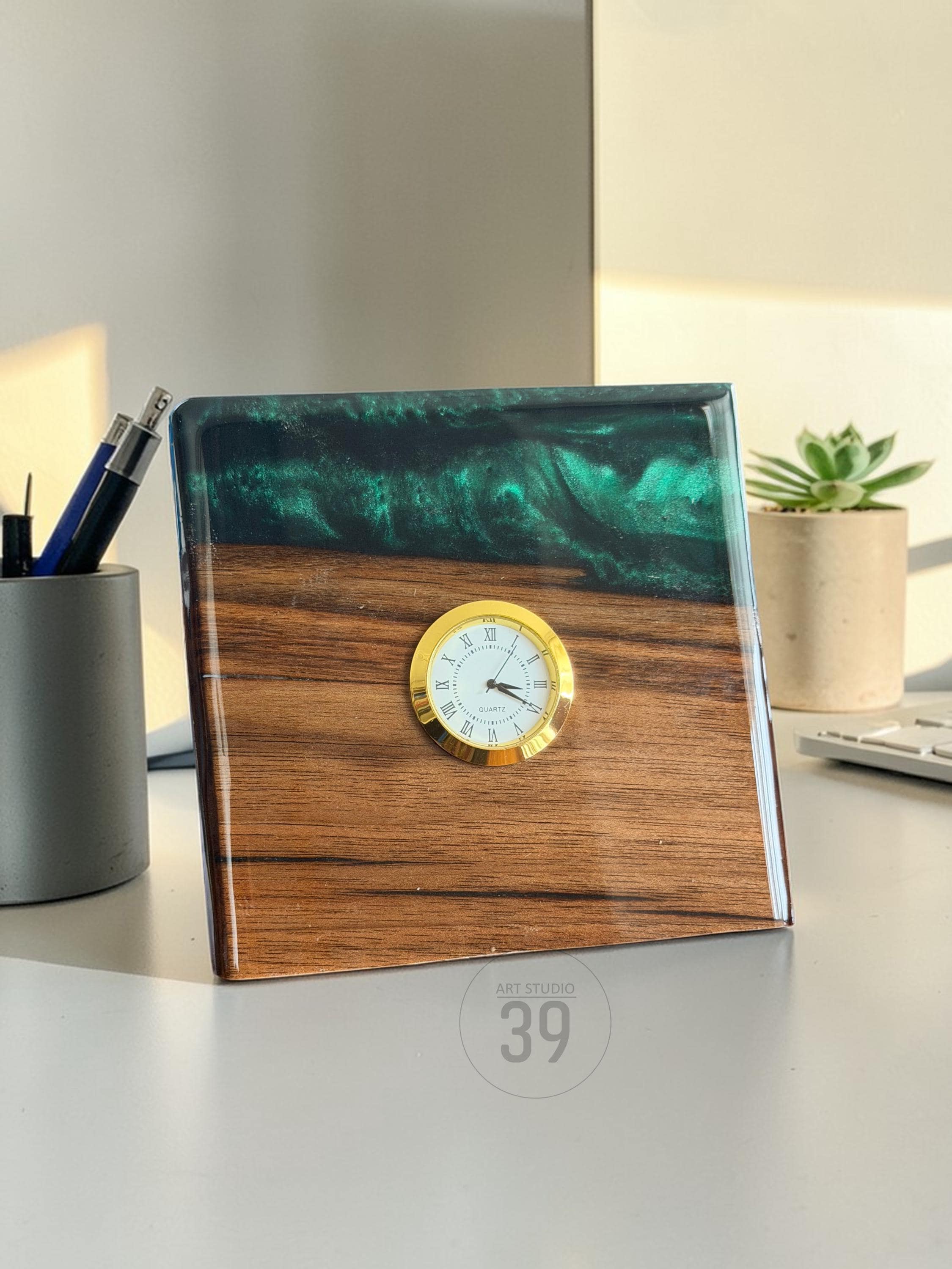 A square desk clock with a wooden base and a top section of swirling green resin. The clock face is gold-colored with Roman numerals. The text "ART STUDIO 39" is printed on the bottom.