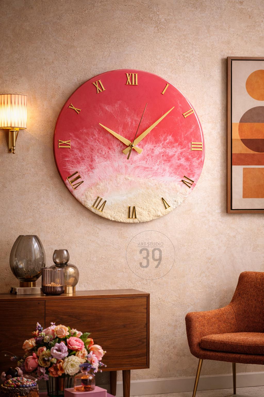 A round wall clock with a red and white gradient design, gold Roman numerals, and gold hands. The clock is mounted on a beige wall. The clock has the text "ART STUDIO 39".
