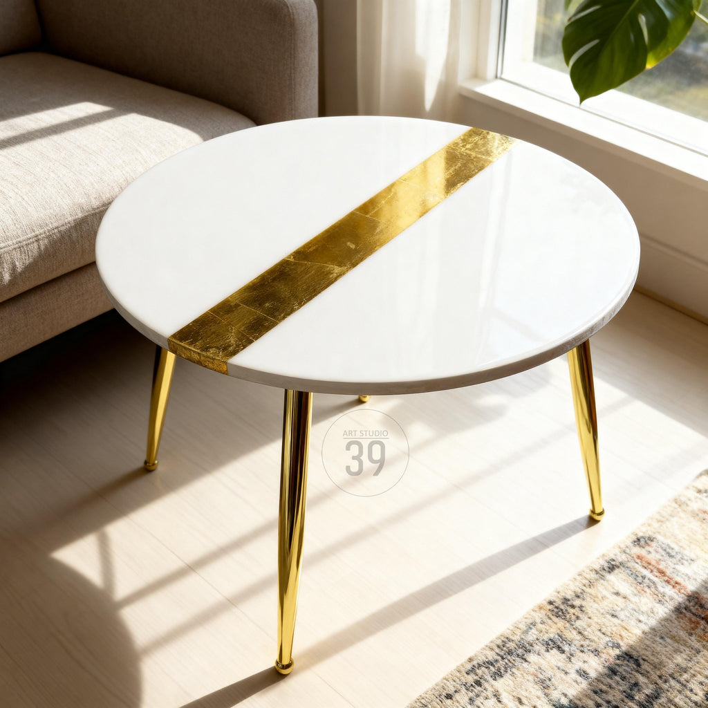 A round white coffee table with a diagonal gold leaf stripe. The table has three gold-colored metal legs. The text "ART STUDIO 39" is printed on the table's surface.