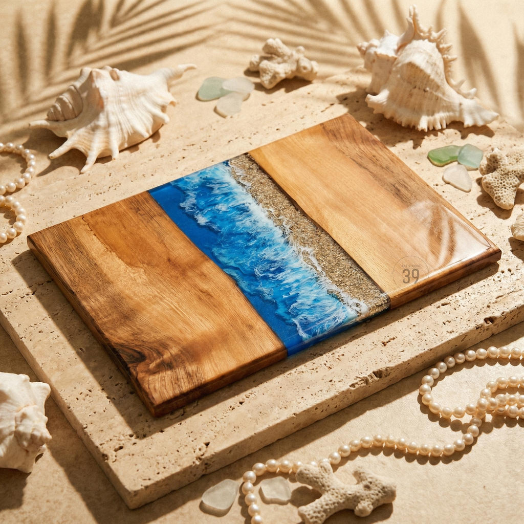 A rectangular wooden serving board with a blue resin wave design and a sandy beach section. The board is surrounded by seashells, pearls, and coral, creating a coastal theme. The number "39" is visible on the board.