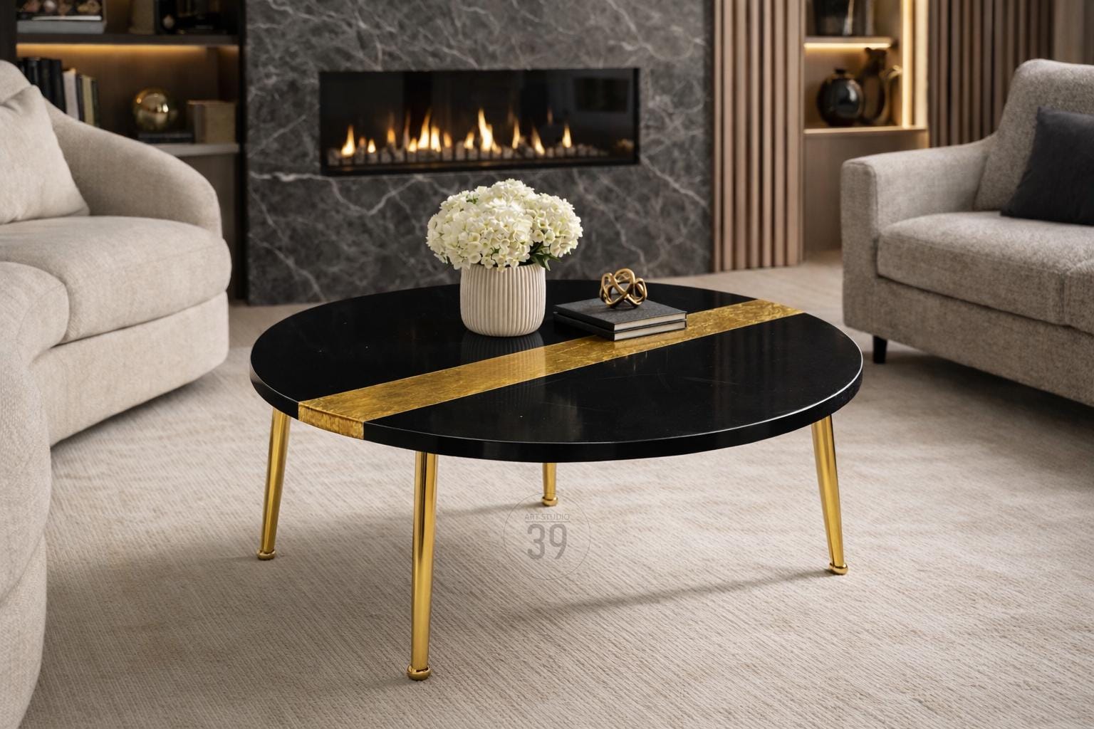 A round black coffee table with a gold stripe and gold legs. The table has a vase of white flowers, a book, and a decorative object on top. The table is 39 inches in diameter.
