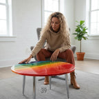A round coffee table with a rainbow-colored top and silver legs. The table has a glossy finish and is approximately 24 inches in diameter. The text "39" is visible on the table.