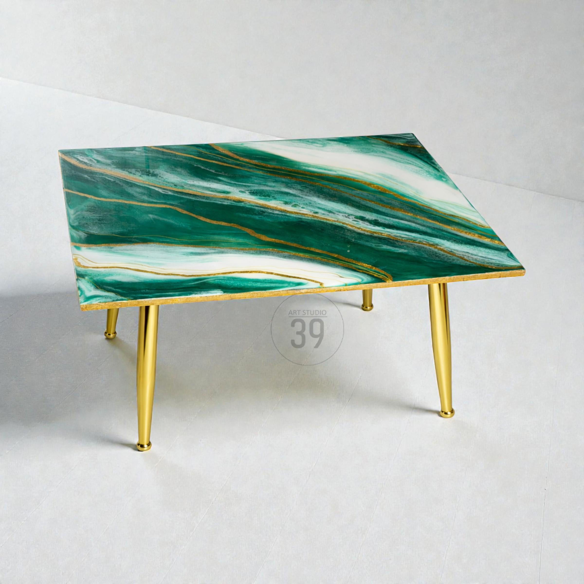 Square coffee table with a green and white marbled design and gold accents. The table has gold legs and a glossy finish. The tabletop features gold veining throughout the green and white surface.