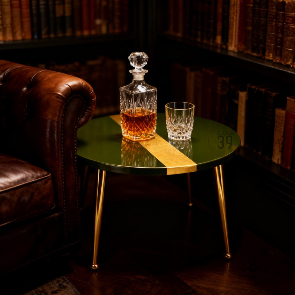 A green and gold accent table with a crystal decanter and a rocks glass. The table has gold legs and a gold stripe down the center. The decanter is filled with amber liquid.