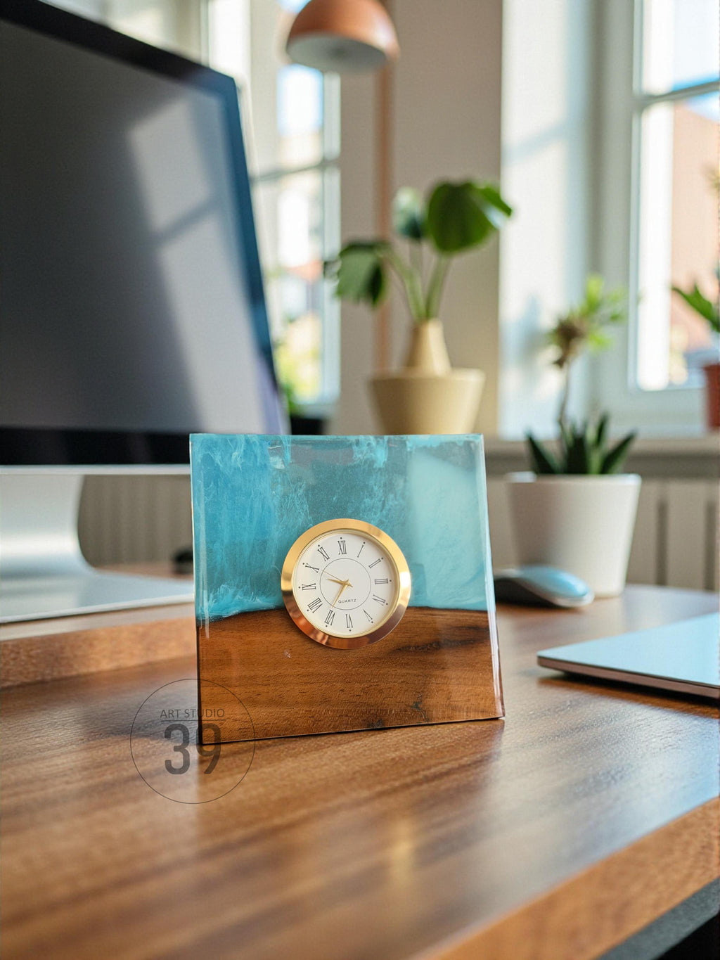 A square desk clock with a gold-colored bezel and white clock face. The clock is set into a block of wood and blue resin. The base of the clock is wood, and the top is blue resin. The text "ART STUDIO 39" is visible.