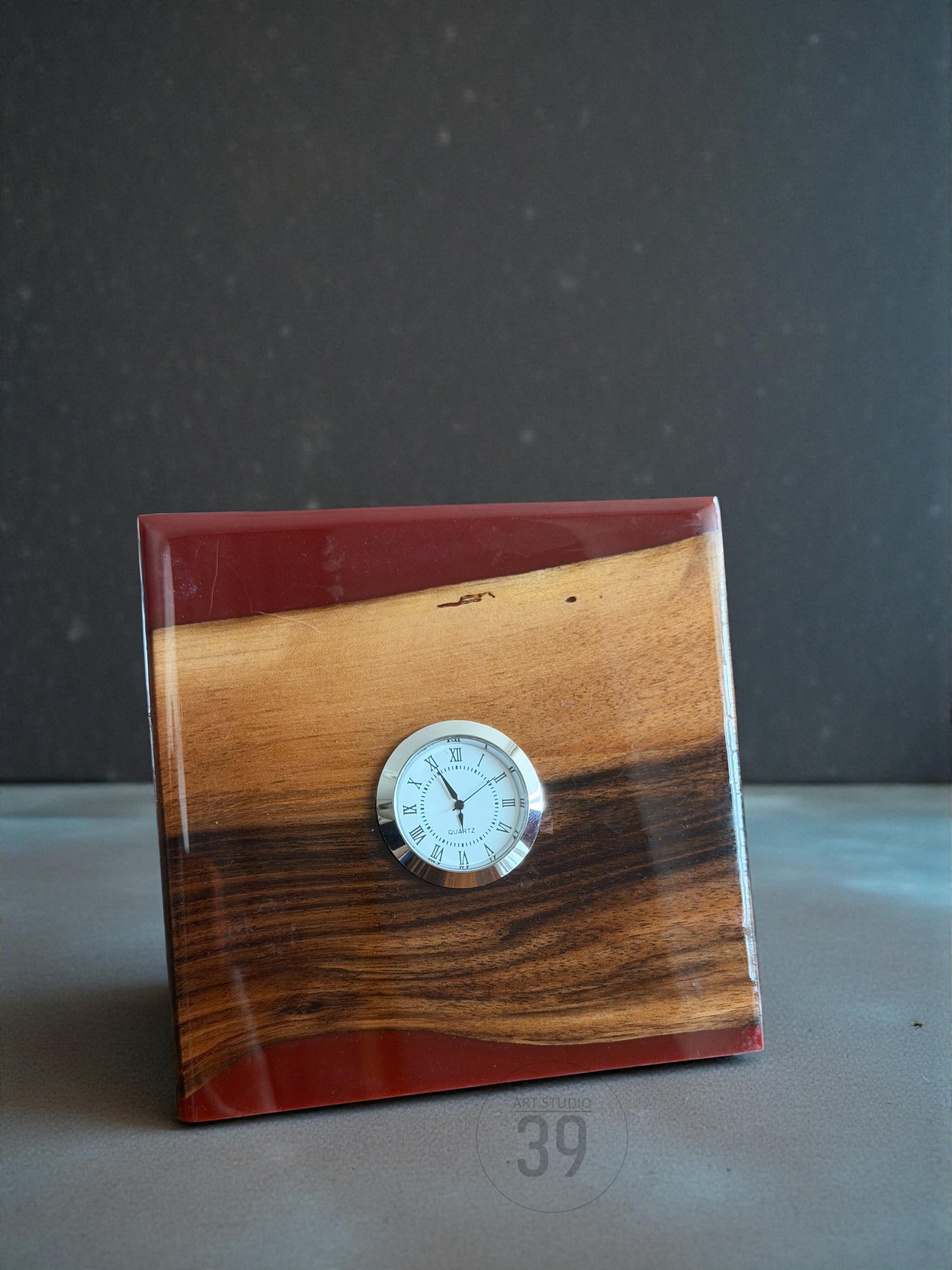 A wooden desk clock with a round clock face. The clock is made of wood with a reddish-brown resin and a silver-colored clock face with black Roman numerals. The number "39" is printed on the bottom right corner.