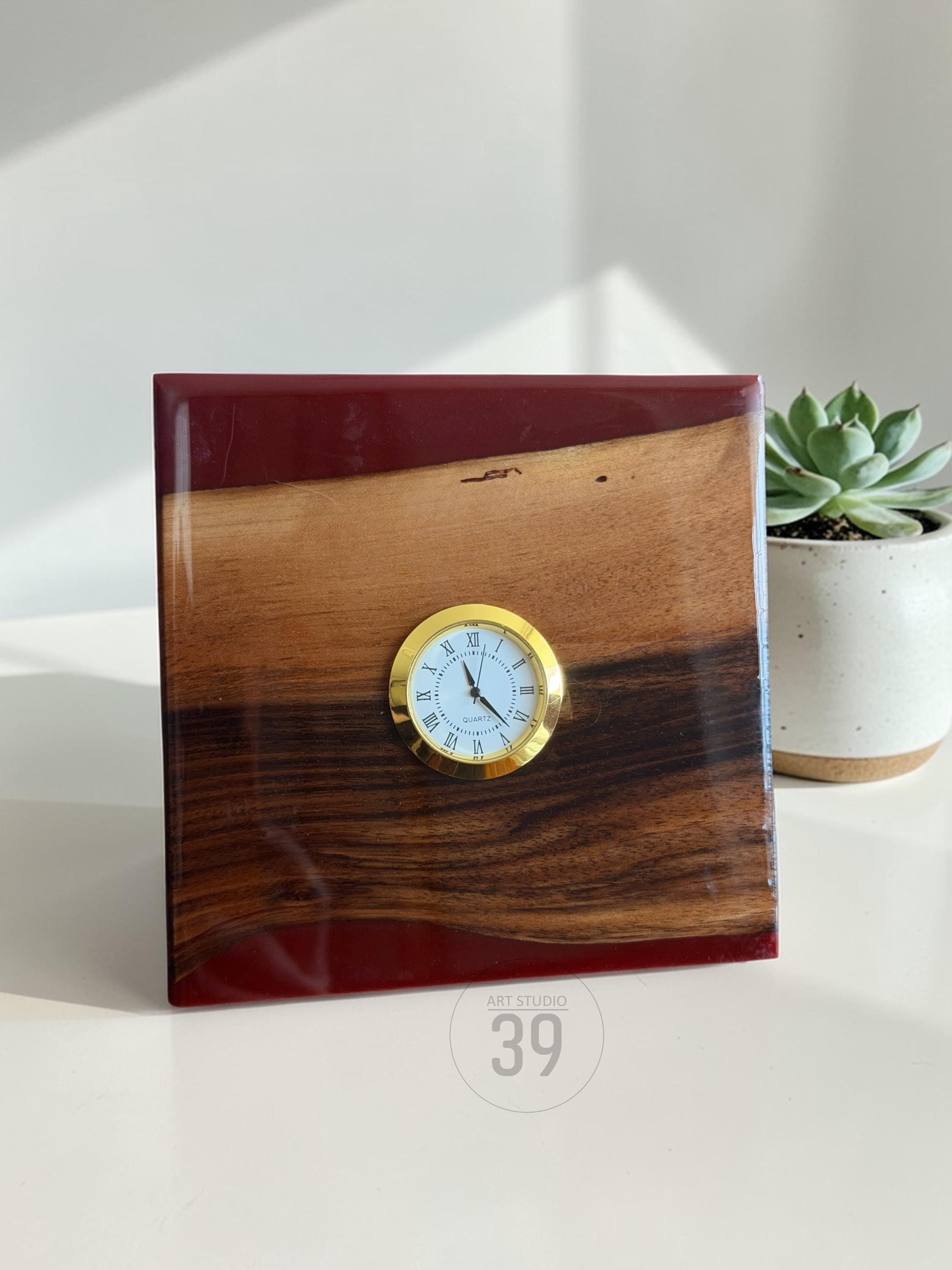 A square wooden clock with a gold-colored clock face and Roman numerals. The clock is made of wood and red resin. The words "ART STUDIO 39" are printed on the bottom of the clock.