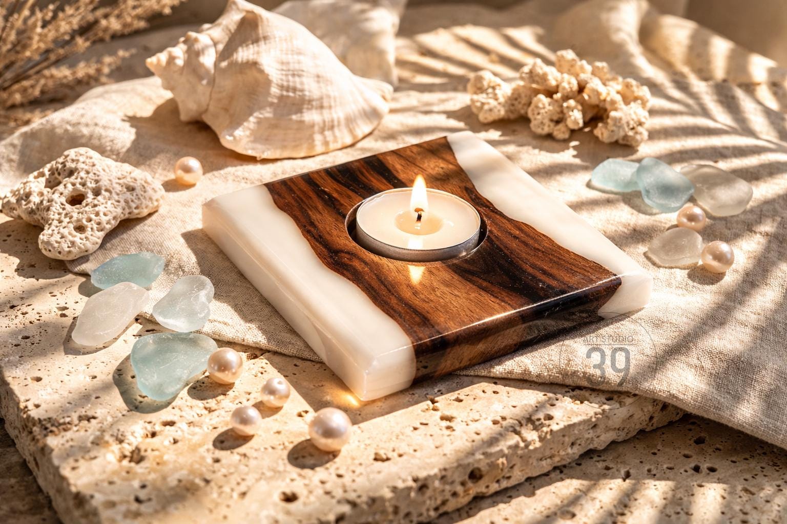 A square candle holder with a lit tea light. The holder features a wood grain center with white resin edges. Decorative elements include seashells, pearls, and sea glass, creating a coastal theme.