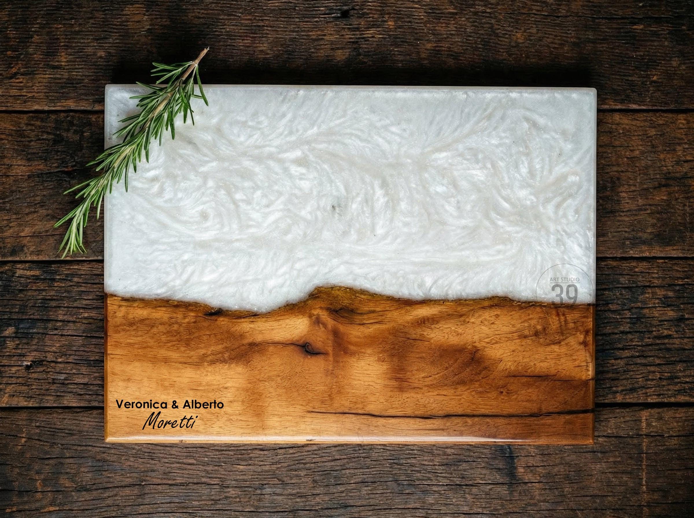 Rectangular wooden serving board with a white resin top and a natural wood base. The board features the text "Veronica &amp; Alberto Moretti" and the number "39". A sprig of rosemary rests on the board.