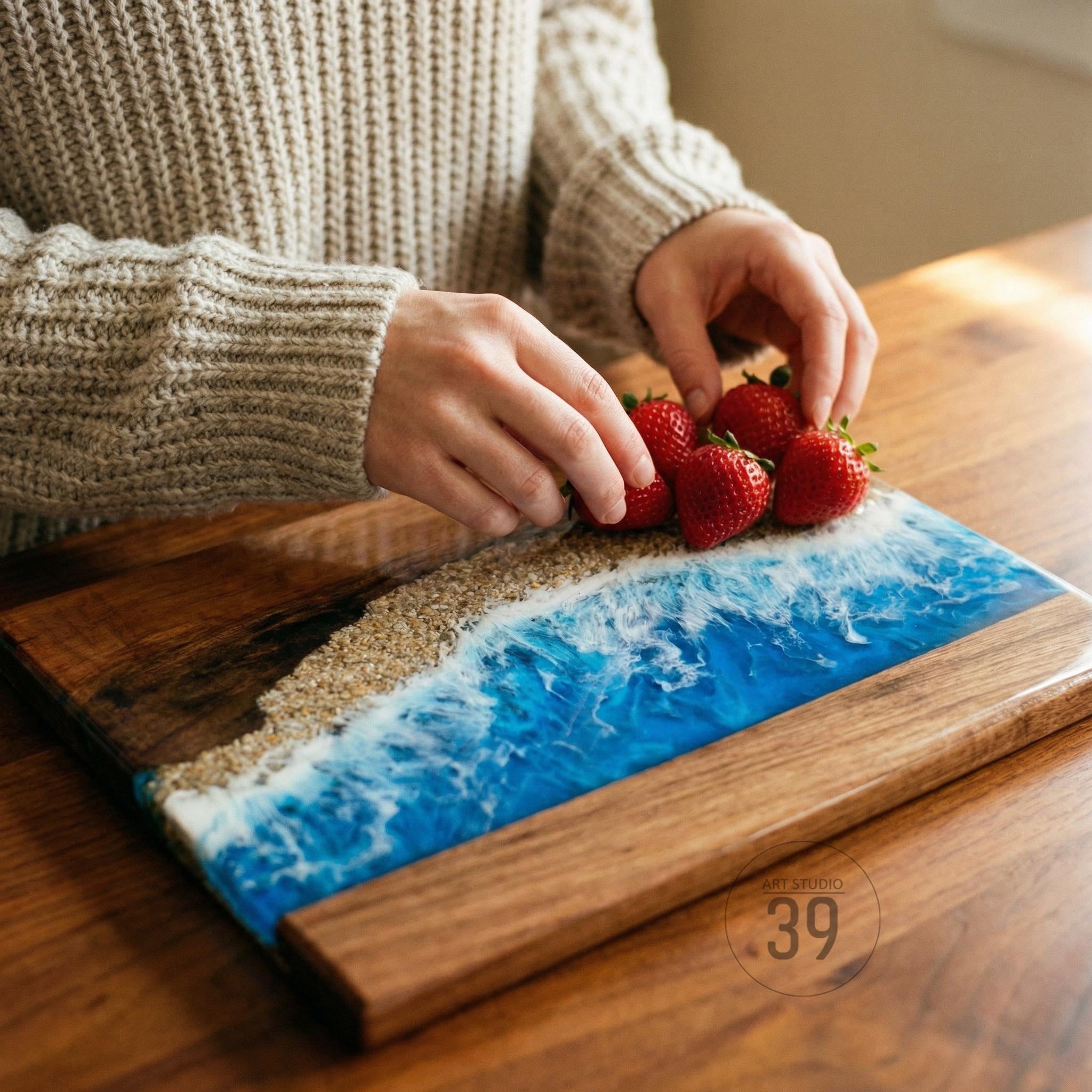 Wooden serving board with a beach-themed design. The board features a wave design with blue resin and sand-colored accents. Fresh red strawberries are placed on the board. The board has the text "ART STUDIO 39".