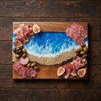 A wooden charcuterie board with a blue and white resin ocean design. The board is decorated with salami, prosciutto, olives, and figs. The number 39 is etched into the wood.
