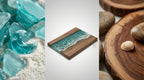 A wooden serving board with a resin ocean design. The board features a rectangular shape with a light brown wood border and a turquoise resin center depicting ocean waves. The image also includes sea glass and wood slices.