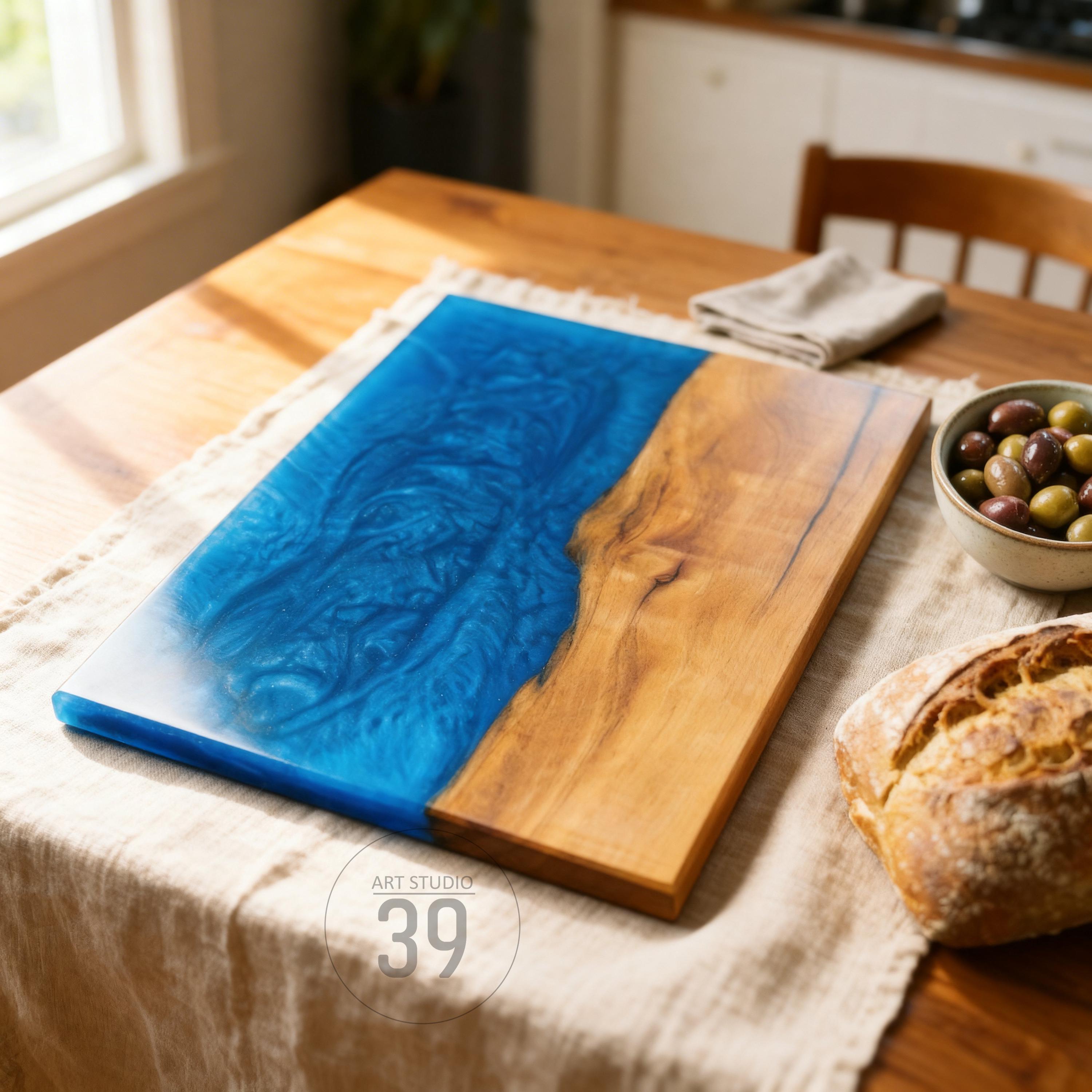 A rectangular wooden serving board with a blue resin river design. The board is approximately 18 inches long and 10 inches wide. The text "ART STUDIO 39" is printed on the board.