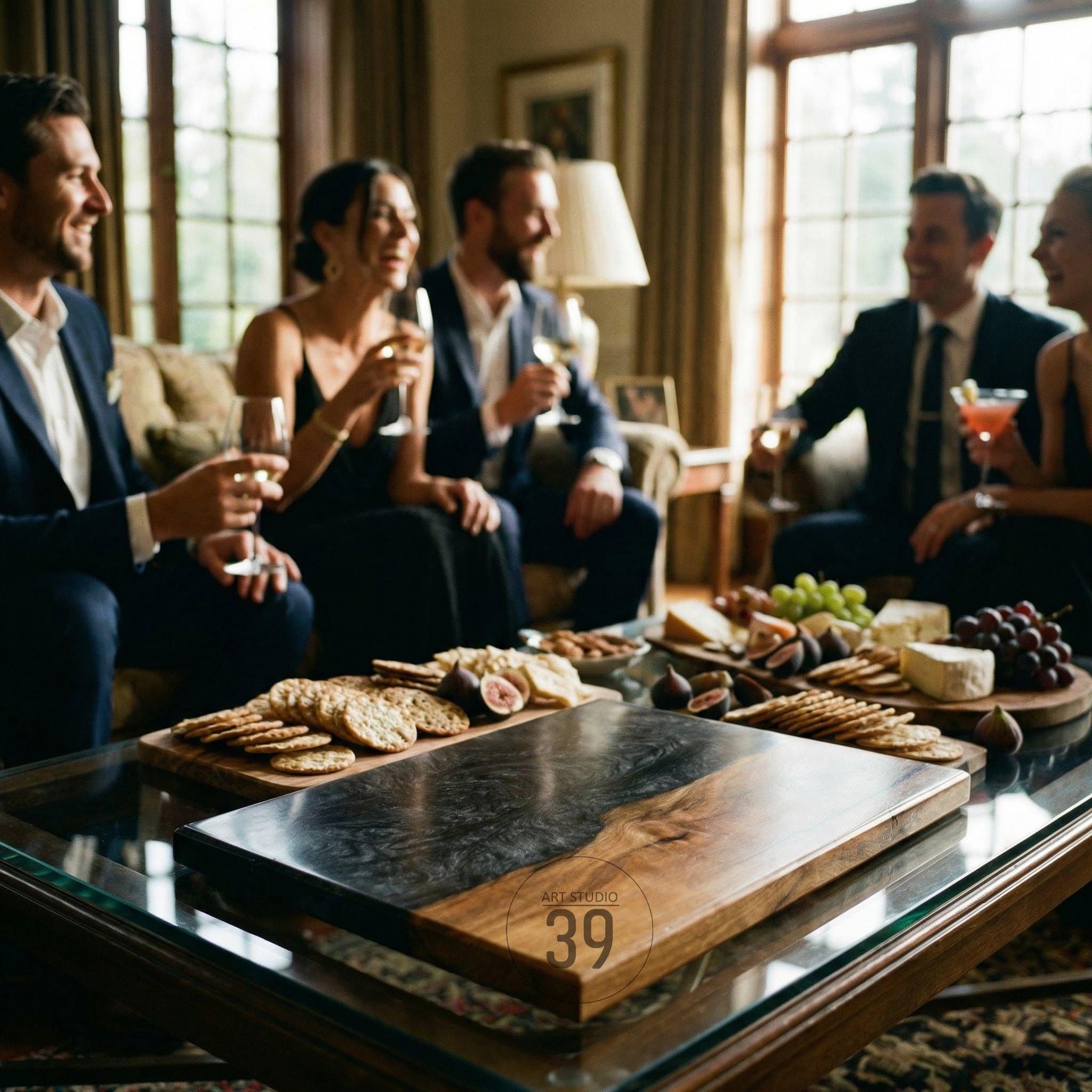 A rectangular wooden serving board with a dark, marbled epoxy resin section. The board is on a glass table with a gathering of people in the background. The board has the text "Art Studio 39".