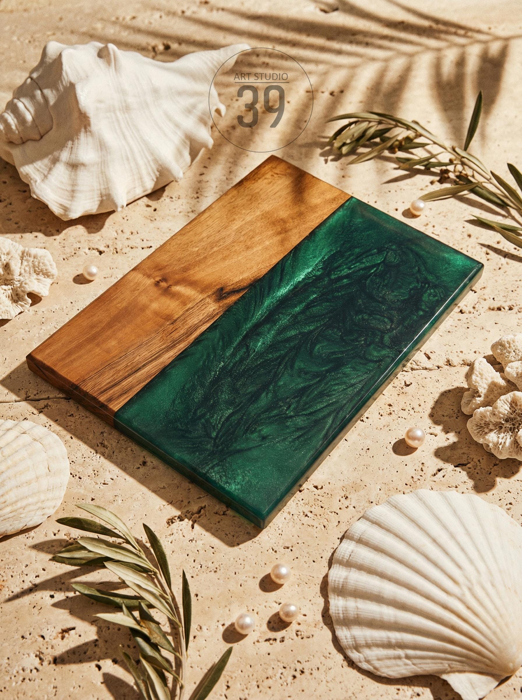 A rectangular wooden serving board with a section of deep green resin. The board is surrounded by seashells, pearls, and greenery. The text "ART STUDIO 39" is in the upper right corner.