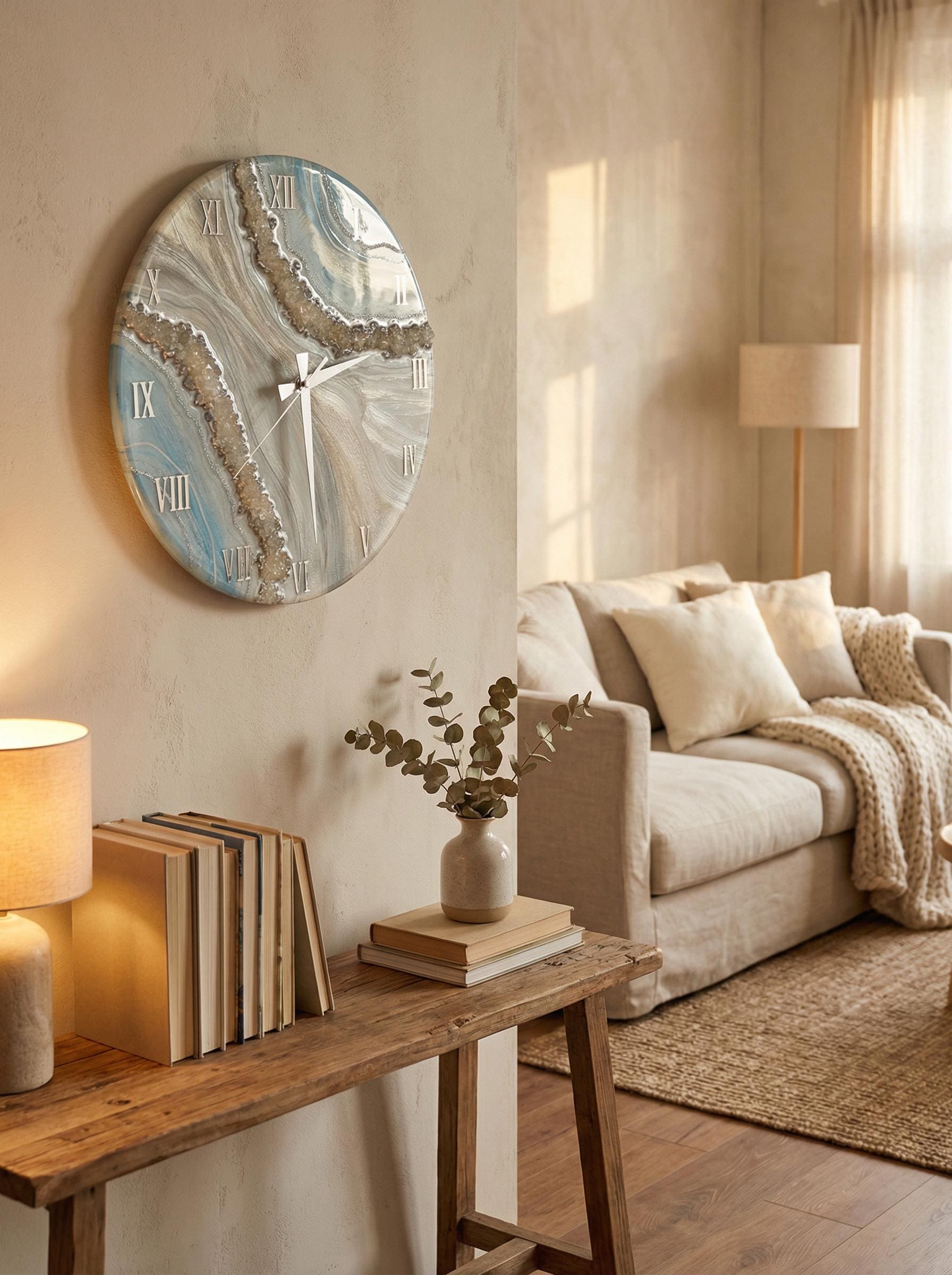 An oval wall clock with a blue, white, and beige marbled design. The clock has silver hands and Roman numerals. The clock is mounted on a beige wall in a living room setting.