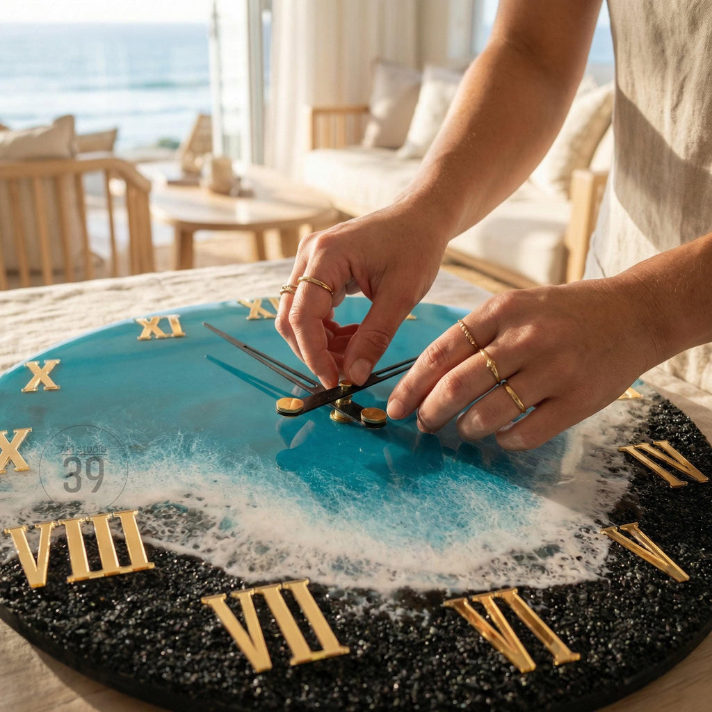 A round wall clock with a blue and black ocean-themed design. The clock face features gold Roman numerals and hands. The clock has a resin finish, with a wave-like pattern and a black, textured border.