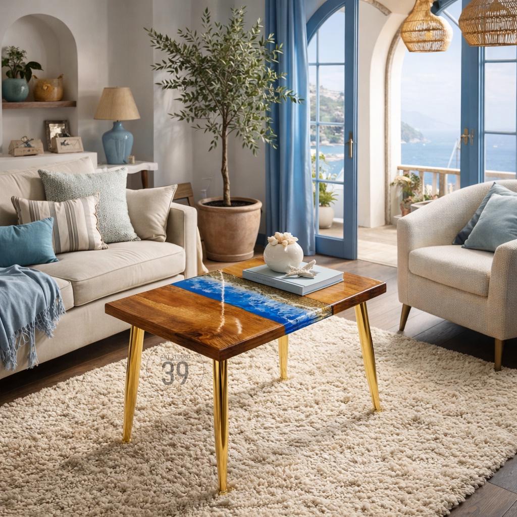 A wooden coffee table with a blue resin river design. The table has a rectangular top with gold-colored metal legs. The table is in a living room with a beige sofa, armchair, and a fluffy rug.