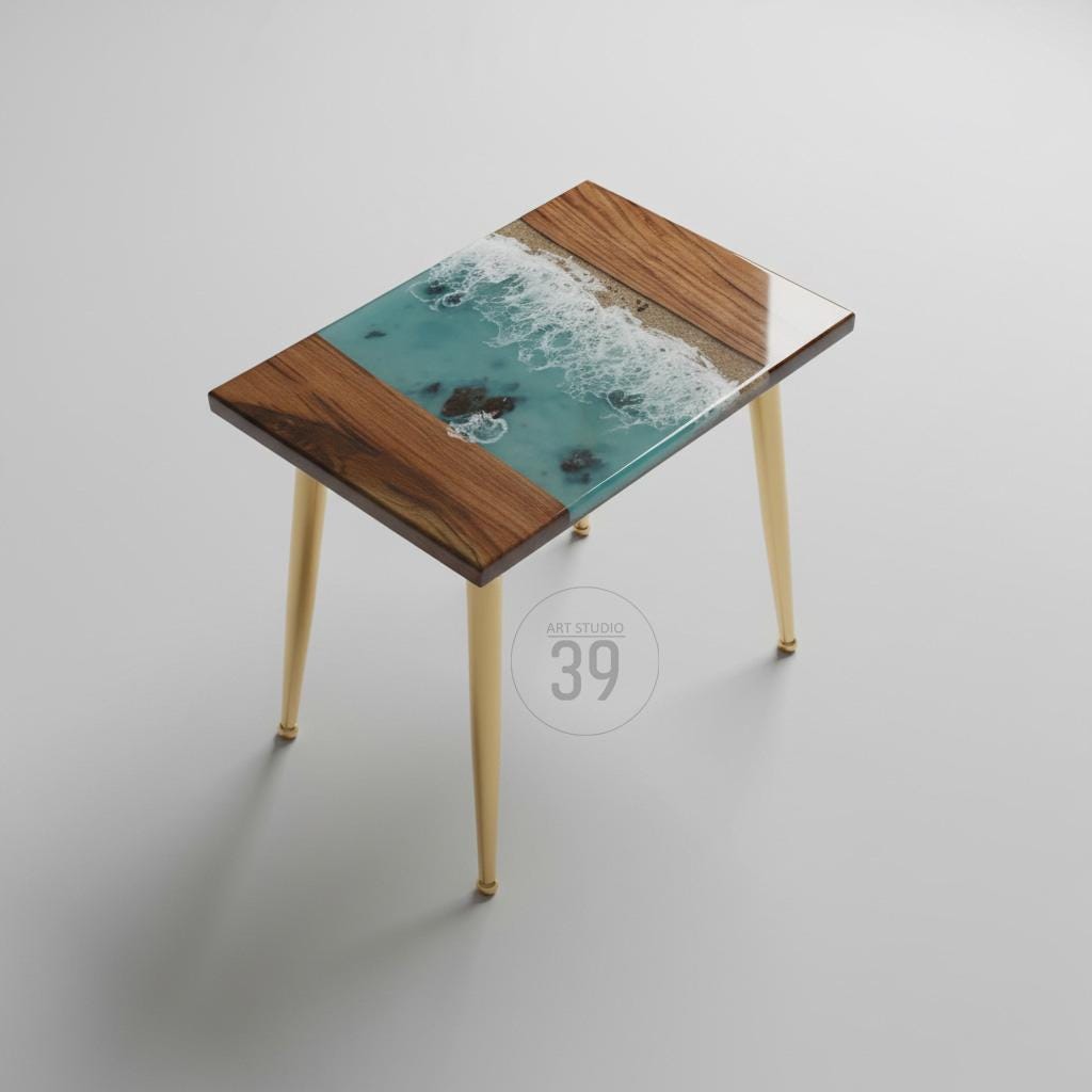 A small, rectangular side table with a unique design. The tabletop features a turquoise resin ocean scene with white waves, framed by dark wood. The table has gold-colored, tapered legs. The text "ART STUDIO 39" is in a circle on the table.