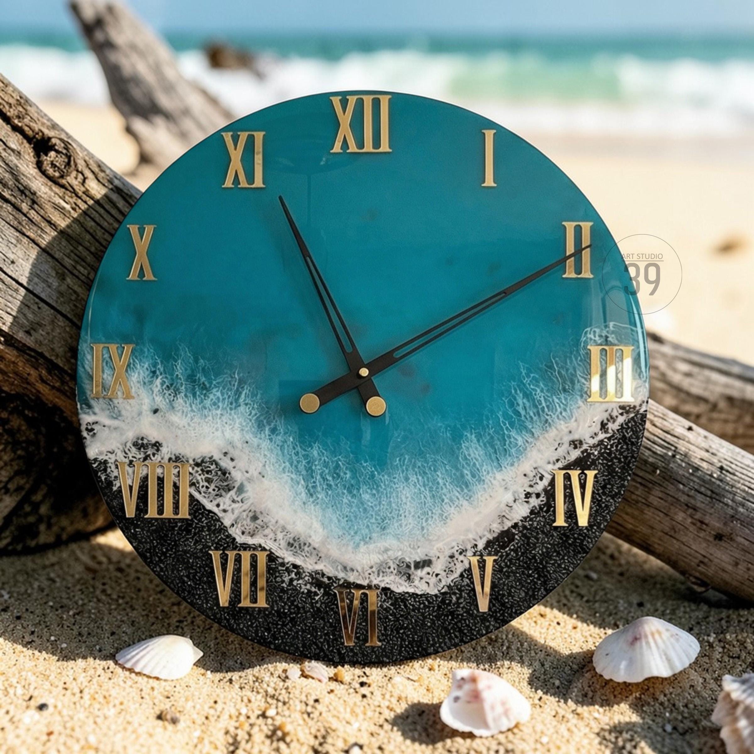 Round wall clock with a teal and black design, featuring gold Roman numerals. The clock face has a wave-like pattern with a black base, resembling a beach scene. The clock hands are black.