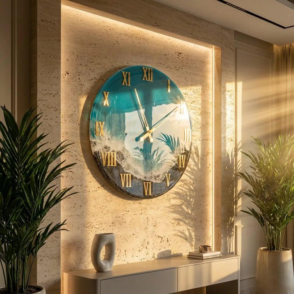 A large, round wall clock with a coastal design. The clock face features a blue and white ocean scene with gold Roman numerals and hands. The clock is mounted on a textured beige wall, with a modern interior design.