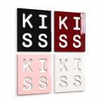 Four square wall art panels arranged in a grid. Each panel features the word KISS cut out in a bold, block font. The panels are colored black, deep red, light pink, and white, all with a smooth, glossy finish and clean edges.