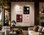 Four square wall art panels arranged in a grid, each featuring the word LOVE cut out in a bold, blocky font. The top left panel is white, the top right is black, the bottom left is deep red, and the bottom right is light pink.