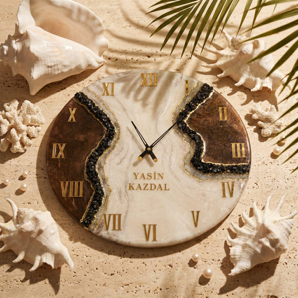 A round wall clock with a white and brown marbled surface, featuring gold Roman numerals and black clock hands. A central band of black crushed stone accents the face, which displays the text YASIN KAZDAL in gold lettering.