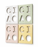 Four rectangular wall tiles arranged in a square grid. Each tile features cut-out letters spelling CICI and CIAO. The tiles are colored white, light green, pale pink, and soft yellow, all with a smooth, glossy, reflective finish.