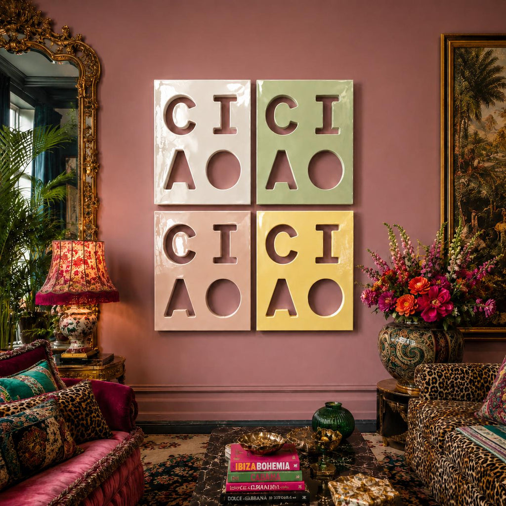 Four square wall art panels arranged in a grid, each featuring the word CIAO cut out in a bold, block font. The top left panel is white, the top right is light green, the bottom left is light pink, and the bottom right is yellow.