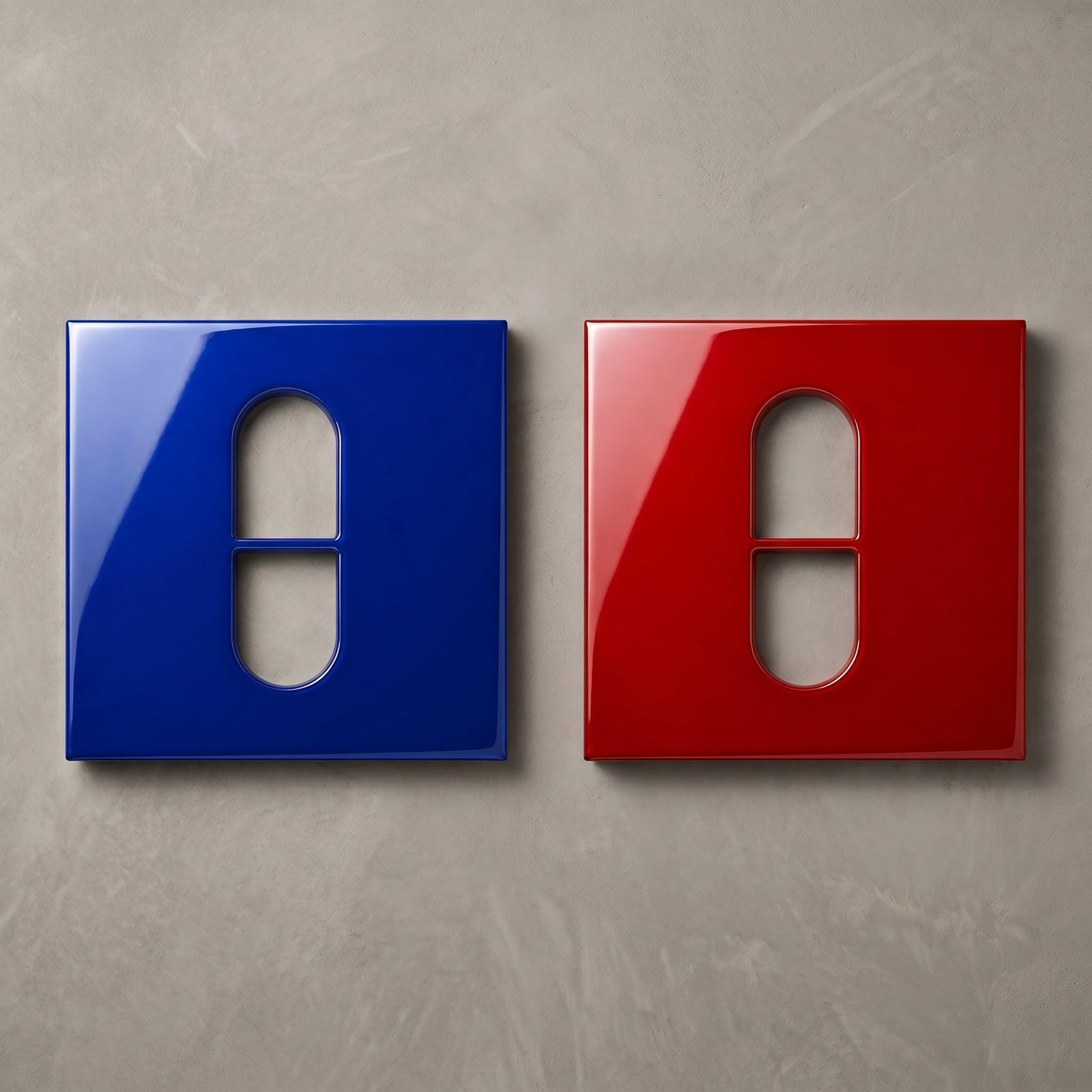 Two square wall plates with a glossy finish, one in deep blue and one in vibrant red. Each plate features a central vertical pill-shaped cutout divided by a horizontal bar, designed for a standard light switch or electrical outlet.