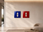 Two square wall art pieces, one in deep blue and one in vibrant red, each featuring a centered, vertical, pill-shaped cutout. The glossy surfaces reflect light, creating a clean, geometric display on the wall surface.