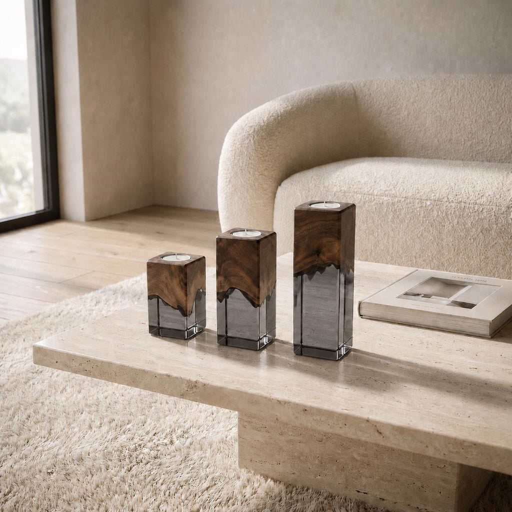 Three square candle holders of varying heights, each featuring a dark brown natural wood top section with a wavy edge and a clear glass base. The holders are arranged in a row, with a small white candle placed inside each top opening.