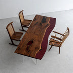 A rectangular dining table featuring a live-edge wood slab with a dark red resin inlay and clear acrylic legs, accompanied by three wooden chairs with vertical slat backrests and angled frames, arranged in a high-angle view.