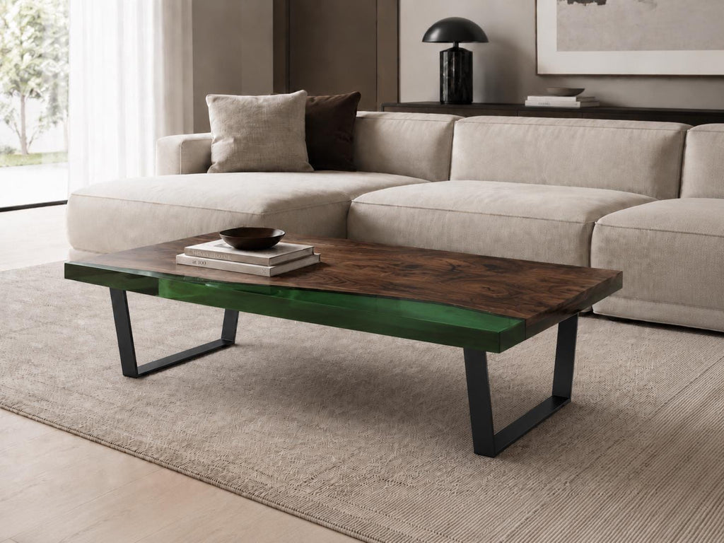 A rectangular coffee table featuring a natural dark wood slab top with a live edge, accented by a translucent emerald green resin inlay along the side. The table is supported by two black metal U-shaped legs on a flat base.