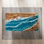A rectangular coffee table featuring a natural wood slab with a prominent grain pattern on both ends, separated by a central section of blue resin designed to resemble ocean waves with white foam detailing across the surface.
