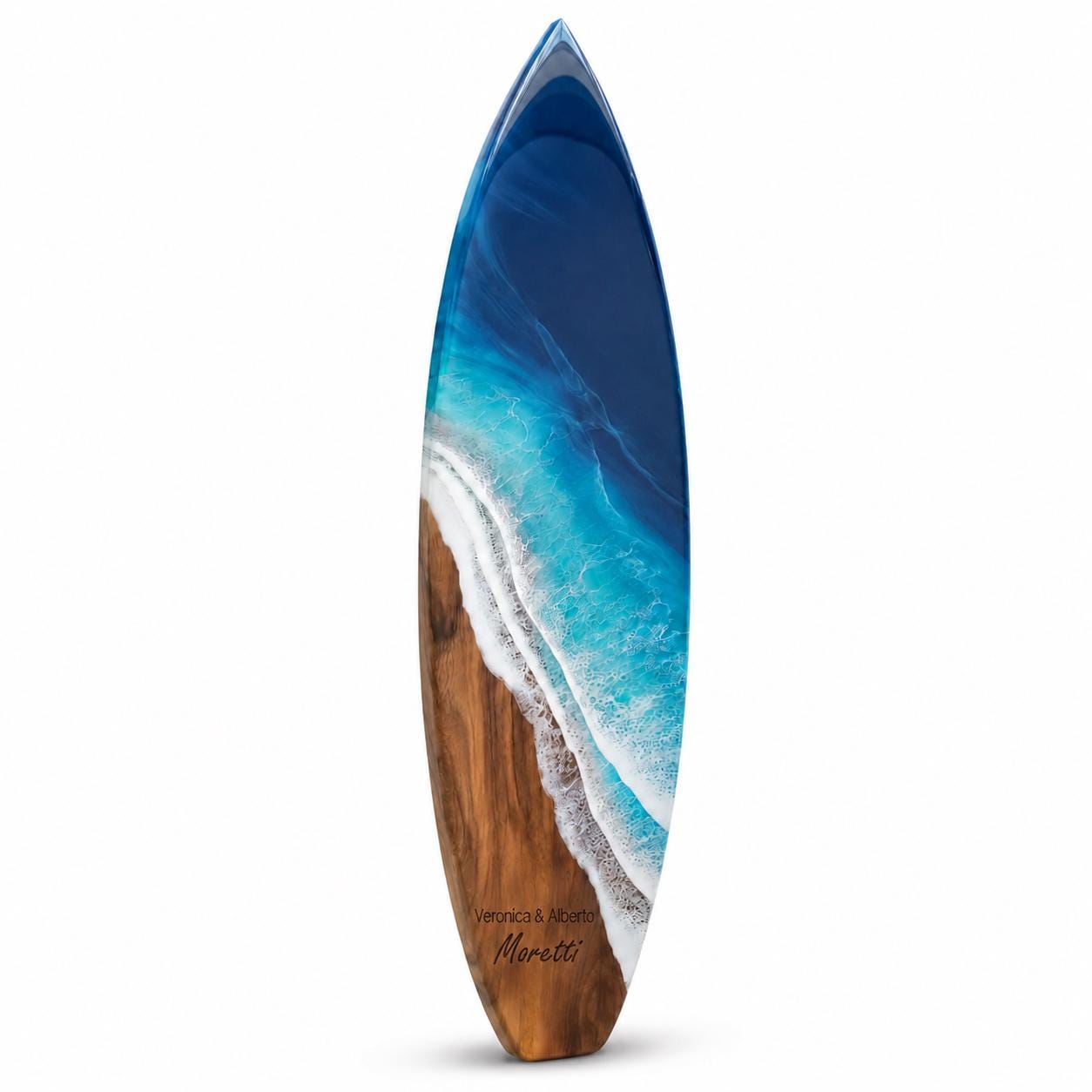 A surfboard featuring a wood grain base that transitions into a blue and white resin ocean wave design. The board displays the text Veronica &amp; Alberto Moretti in a dark script font near the bottom on the wooden section.