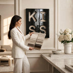 A fabric sample book featuring a range of neutral-toned swatches in shades of cream, beige, taupe, and brown, held open to display the various textures and colors available for selection in a professional interior design setting.