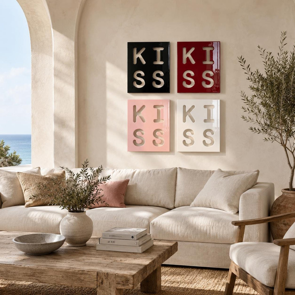 Four square wall art panels arranged in a grid, each featuring the word KISS in a cutout style. The top left panel is black, the top right is red, the bottom left is light pink, and the bottom right is white, all with a glossy finish.