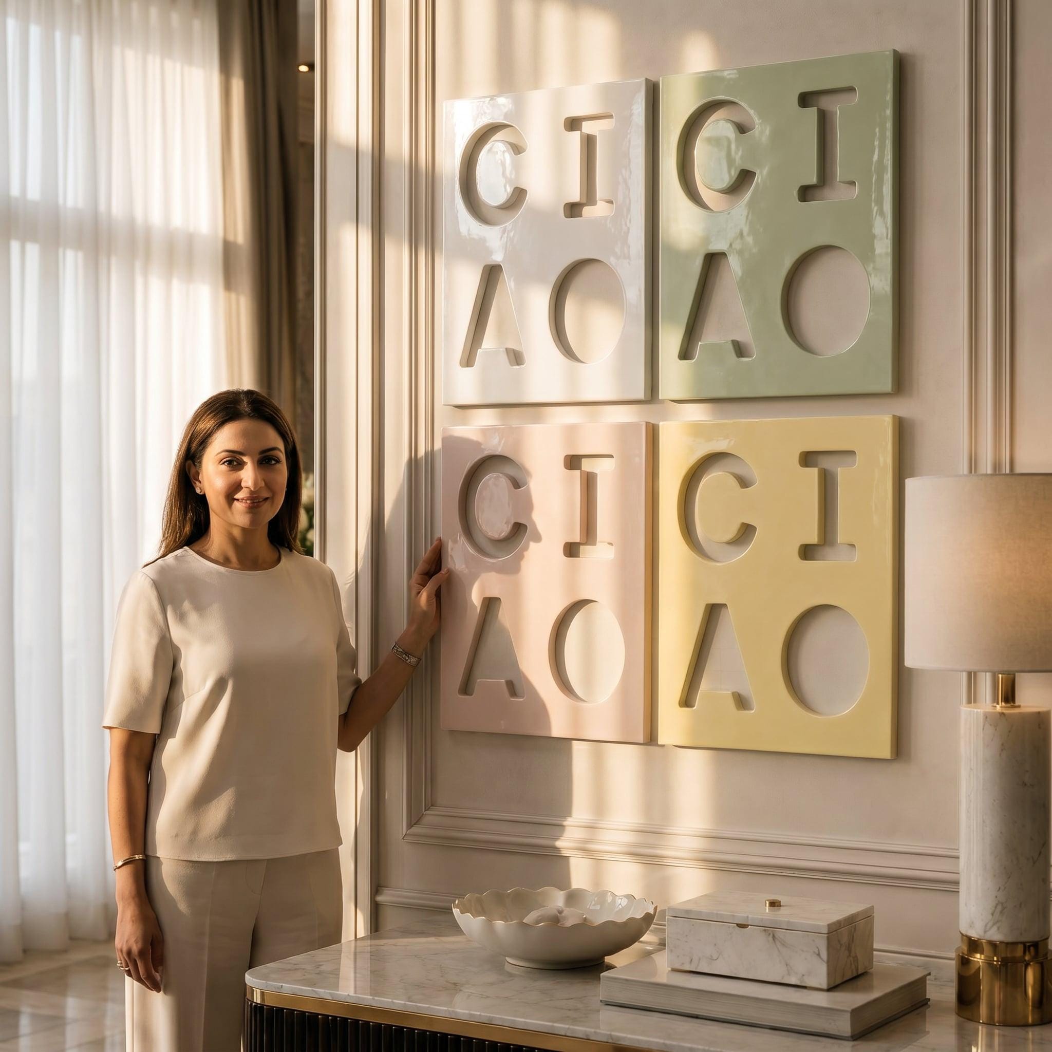 Four square wall panels arranged in a grid, each featuring cut-out letters spelling CICI and AOA. The top-left panel is white, top-right is sage green, bottom-left is pale pink, and bottom-right is pale yellow, all mounted on a wall.