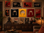 A gallery wall featuring framed posters with titles like Night Shift, Reservoir Nights, Life, Trouble Finds Me, and Deadline, alongside three square panels in black, yellow, and red with central cutouts, displayed above a dark wood sideboard.