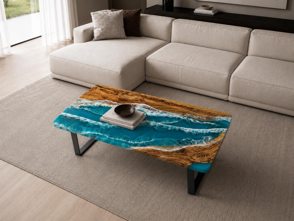 A rectangular coffee table featuring a natural wood slab with a live edge and a central resin inlay designed to resemble ocean waves with shades of turquoise, blue, and white foam. The table is supported by black metal legs.