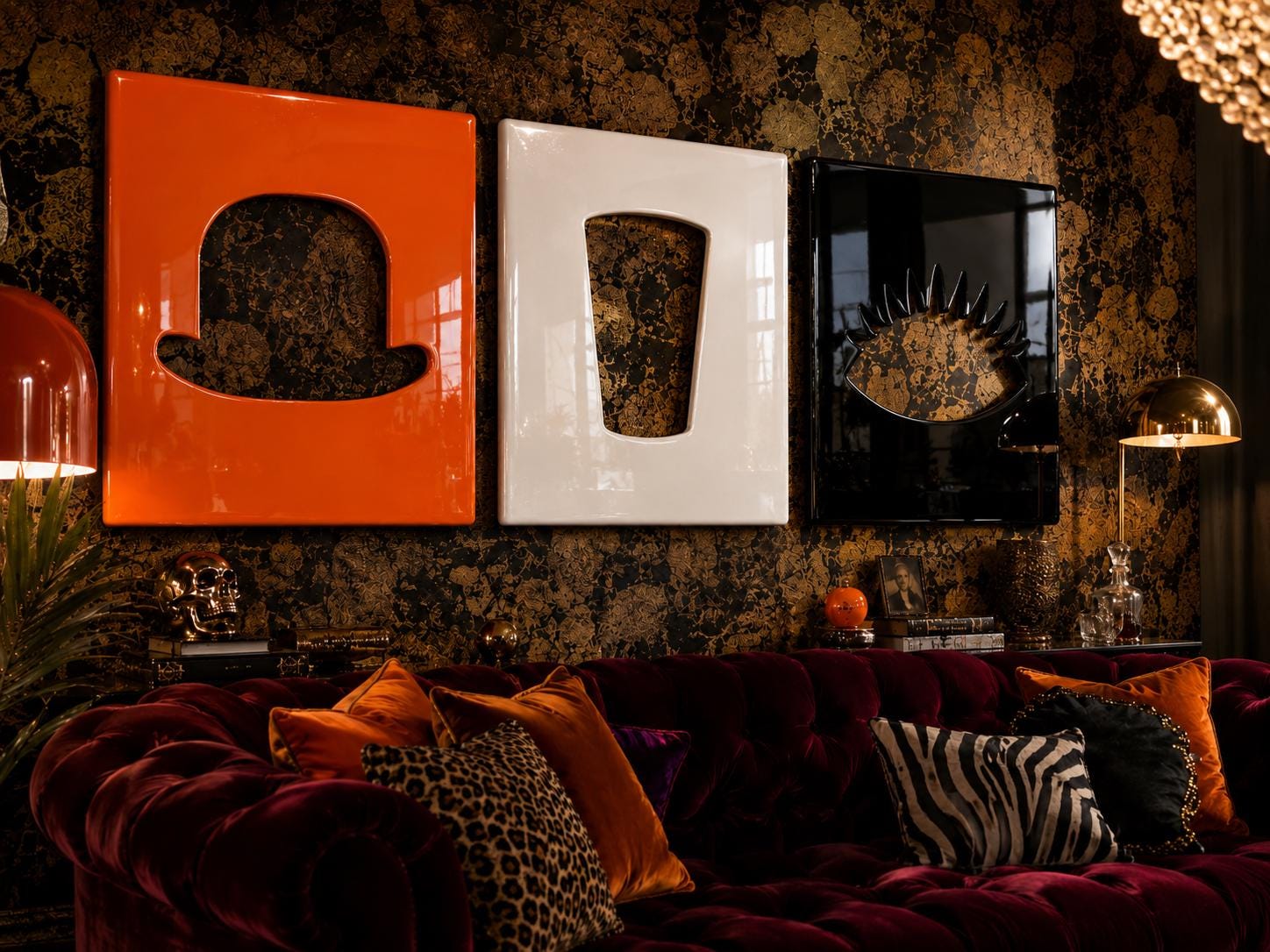 Three rectangular wall art panels featuring glossy finishes in orange, white, and black. The orange panel displays a bowler hat cutout, the white panel shows a trapezoidal cutout, and the black panel features a stylized eye design.