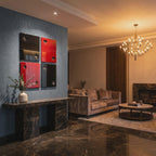 Four square wall art panels arranged in a grid, featuring glossy black and red surfaces with cut-out playing card suit symbols including clubs, hearts, diamonds, and spades, mounted on a blue wall above a dark marble console table.