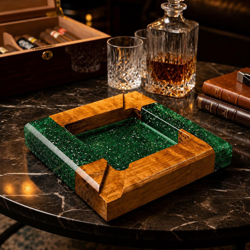A square ashtray constructed from polished natural wood and translucent emerald green resin with embedded glitter particles. The design features four integrated cigar rests at the corners, combining smooth wood grain with a vibrant, sparkling green center basin.
